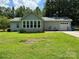 View of the side of the house, showing a sunroom with many windows and the detached garage with a white garage door at 13221 Brandywine Ln, Midland, NC 28107