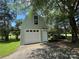 View of the detached garage and driveway, with a white garage door, exterior door, and a small window above at 13221 Brandywine Ln, Midland, NC 28107