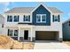 New construction two-story home with white siding, blue accents, a two-car garage, and stone details at 2030 Puddle Pond Rd, Indian Trail, NC 28079