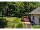 Fenced backyard with a well-maintained lawn, mature trees, and a wood deck with a seating area at 2124 Congress Ct, Kannapolis, NC 28083