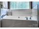 Close-up of a luxurious white bathtub featuring stylish faucet fixtures and a glass block window at 2124 Congress Ct, Kannapolis, NC 28083