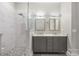 Well-lit bathroom featuring a double vanity, stylish mirrors, and a glass-enclosed shower with modern tile at 229 N Church St # 100, Charlotte, NC 28202