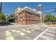 Street-level view of a commercial building featuring classic brickwork, large windows, and surrounding trees at 229 N Church St # 100, Charlotte, NC 28202
