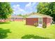 Backyard featuring a detached garage with a white door surrounded by greenery and a lawn at 24132 Nc Hwy 73 Hwy, Albemarle, NC 28001