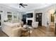 Cozy living room with a fireplace, large windows, modern ceiling fan, and hardwood floors at 3006 Constitution Ln, Gastonia, NC 28056