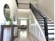Elegant foyer with hardwood floors, staircase with black railing, and a view into the living area at 305 Pleasant Hill Se Dr, Concord, NC 28025