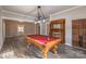 Open game room showcases a beautiful pool table, hardwood floors, and a lovely wooden fireplace at 3607 Austin Rd, Monroe, NC 28112