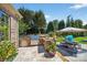 A stone-clad outdoor kitchen includes stainless steel appliances, a grill, and bar seating for entertaining at 3981 Spinnaker Pl, Denver, NC 28037