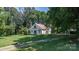 Exterior shot displaying a sunroom, well-manicured lawn, and a mature tree canopy, creating a private and appealing residence at 5560 Springs Rd, Conover, NC 28613