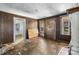 Living room features damaged floor, wood paneled walls, doorway and windows at 5560 Springs Rd, Conover, NC 28613