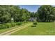 Scenic view of a home surrounded by mature trees and lush greenery, accessible via a gravel driveway, blending seclusion and charm at 5560 Springs Rd, Conover, NC 28613