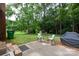 Relaxing backyard patio with seating area and grill, nestled amidst lush greenery and mature trees at 5727 Faulconbridge Rd, Charlotte, NC 28227