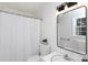Bright bathroom features a tub with shower, white tiles, toilet, and a framed mirror at 5727 Faulconbridge Rd, Charlotte, NC 28227
