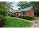 Charming one story brick home with trimmed bushes, green lawn, and mature shade trees in a quiet neighborhood at 5727 Faulconbridge Rd, Charlotte, NC 28227