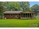 Brick house exterior with screened in porch, lawn and mature trees at 6039 Donna Dr, Charlotte, NC 28213