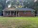 Charming single-story brick home with a cozy front porch and mature trees surrounding the property at 6039 Donna Dr, Charlotte, NC 28213