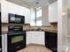 Well-lit kitchen with black appliances, white cabinets, and open view to living area at 621 Pine Links Dr, Tega Cay, SC 29708