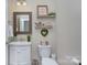 Cozy half-bathroom featuring wainscoting, rustic decor, and decorative shelving above the toilet at 6326 Jepson Ct, Charlotte, NC 28214