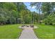 View of the backyard with a fire pit, seating, and a charming swing. Surrounded by lush greenery and trees at 640 Lochaven Rd, Weddington, NC 28173