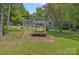 View of the beautiful blue home and surrounding landscape, along with a stone fire pit, deck, and decorative swing at 640 Lochaven Rd, Weddington, NC 28173