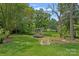 View of the backyard with a charming swing, and a pond. Surrounded by lush greenery and trees at 640 Lochaven Rd, Weddington, NC 28173