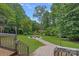 View of the backyard featuring a fire pit surrounded by gravel and seating, surrounded by lush greenery and trees at 640 Lochaven Rd, Weddington, NC 28173