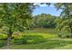 View of the tranquil pond surrounded by lush greenery and trees, offering a serene natural backdrop to the property at 640 Lochaven Rd, Weddington, NC 28173