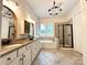 A bathroom featuring a double sink, a tub, and a shower with a glass door at 7076 Brookstone Ln, Fort Mill, SC 29707