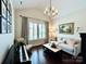 This living room features a chandelier, a piano, a couch, and a window with shutters at 7076 Brookstone Ln, Fort Mill, SC 29707