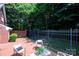 A charming patio space with brick flooring, surrounded by lush greenery and a wrought iron fence at 7554 Bluestar Ln, Charlotte, NC 28226
