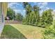 Lush backyard with green grass, mature trees, a stone retaining wall, and a covered patio at 101 Daybreak Ln, Belmont, NC 28012
