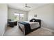 Cozy bedroom featuring a textured wall, comfortable bed, ceiling fan, and natural light from the large window at 10437 Paper Birch Dr, Charlotte, NC 28215