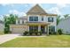 Beautiful two-story home with blue shutters, a covered front porch, and lovely landscaping at 10437 Paper Birch Dr, Charlotte, NC 28215