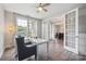 Office with hardwood floors, large windows with curtains, and a seating area with a glass desk at 10437 Paper Birch Dr, Charlotte, NC 28215