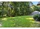 Spacious green backyard featuring a mature tree line, lawn, and an outdoor seating area at 117 Franklin St, Clover, SC 29710