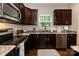 A well-lit kitchen boasts granite countertops, dark cabinets, and stainless steel appliances at 117 Franklin St, Clover, SC 29710