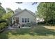 Well-maintained backyard with a stone patio, outdoor seating, lush lawn, and mature trees at 1304 Hammond Dr, Matthews, NC 28104