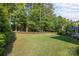 The spacious backyard features manicured lawn with garden beds and a wooded tree line at 16522 Flintrock Falls Ln, Charlotte, NC 28278