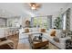 Bright living room features a ceiling fan, a white couch, large windows, and hardwood floors at 16522 Flintrock Falls Ln, Charlotte, NC 28278