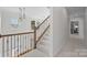Well-lit staircase with carpeted steps, a decorative railing, and modern pendant lighting at 16522 Flintrock Falls Ln, Charlotte, NC 28278