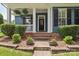Close-up of the house's entryway with a charming front porch, flower pots and healthy shrubs at 17711 North Shore Cir, Cornelius, NC 28031