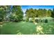 Beautifully manicured backyard with lush green grass, mature trees, and a cozy patio area for relaxation at 18439 Victoria Bay Dr, Cornelius, NC 28031