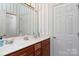 Bathroom with double sinks, light fixtures, patterned wallpaper and a white door at 18534 Carnegie Overlook Blvd # 110, Davidson, NC 28036