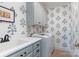 Well-lit laundry room featuring a utility sink, washing machine, blue cabinetry, and patterned wallpaper at 18534 Carnegie Overlook Blvd # 110, Davidson, NC 28036