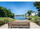 Scenic lake view featuring a bench, lush greenery, and waterfront homes under a clear blue sky, offering a tranquil setting at 18730 Nautical Dr # 102, Cornelius, NC 28031