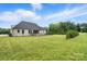 Wide backyard with a dark roof house, green grass and dark fence. Plenty of sunshine and some trees nearby at 19 Berea Baptist Church Rd, Stanfield, NC 28163