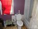 Small bathroom with purple walls, stained floor, toilet, and combination tub/shower at 212 Huffman Rd, Gastonia, NC 28052