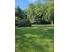 A large grassy front yard featuring a street view and mature trees on a sunny day at 215 9Th St, Spencer, NC 28159