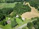 Sprawling aerial view of home and barns, surrounded by lush greenery and open fields at 233 Hicks Rd, Statesville, NC 28625