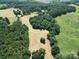 Expansive aerial view of farmland with hay bales surrounded by lush, green trees at 233 Hicks Rd, Statesville, NC 28625